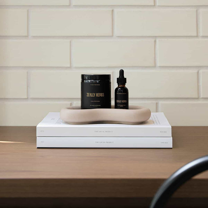 2 items from the parasite & heavy metal detox set, styled on a table with white tiled background and stacked on 2 white books with a beige tray.