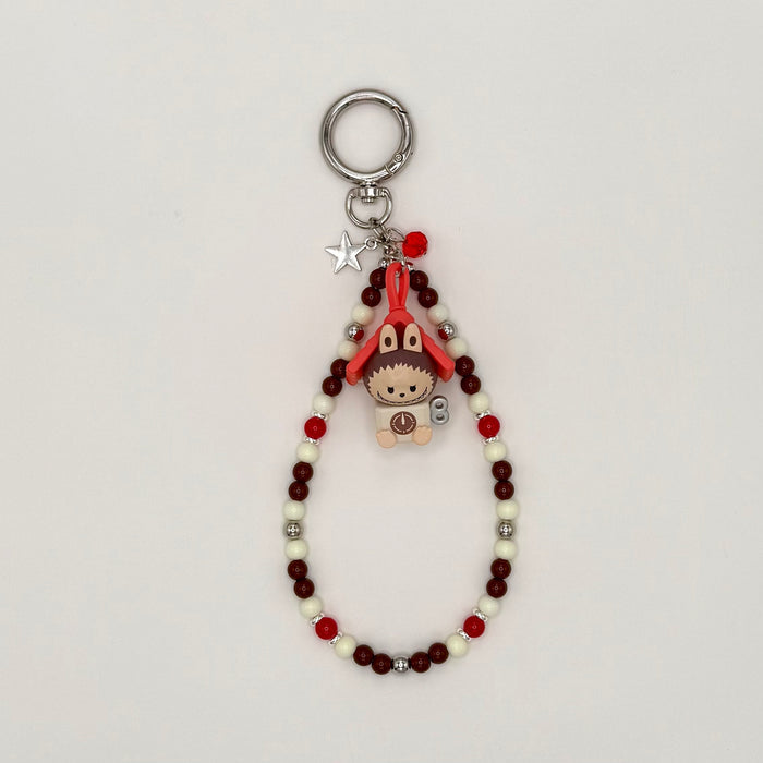 Keychain with beads and small character charm on a light gray background