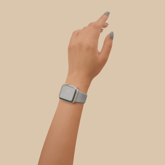 Silver metallic Apple Watch case and screen protector by Coconut Lane shown on wrist with painted nails against beige background.