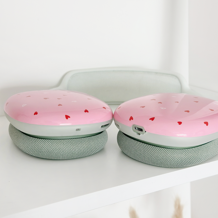 Two pink wireless speakers with heart patterns and gray bases, displayed side by side on a shelf.