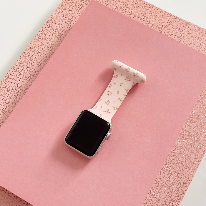 Coconut Lane Apple Watch clip-on fob strap in pink ditsy floral pattern on a pink textured paper background.