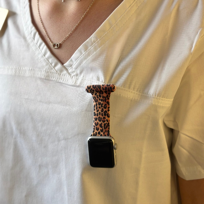 Leopard print Apple Watch clip-on fob strap by Coconut Lane clipped to the chest pocket of a white scrub top.
