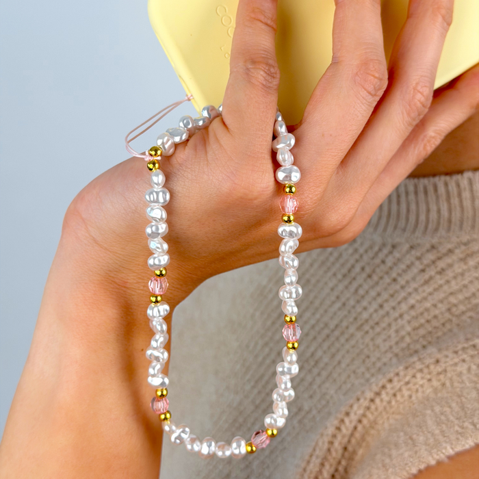 Close up image showing pearl gold and pink phone strap on phone case