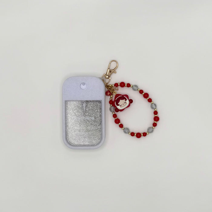 Touchland Power Mist hand sanitizer in a blush pink silicone case with a glitter window on a white background. Attached gold lobster clasp keychain features a Skullpanda chibi charm in a pink hood holding a small item, paired with a beaded wrist strap of pink, orange, and gold star-shaped beads. TOUCHLAND NOT INCLUDED WITH THIS PRODUCT!