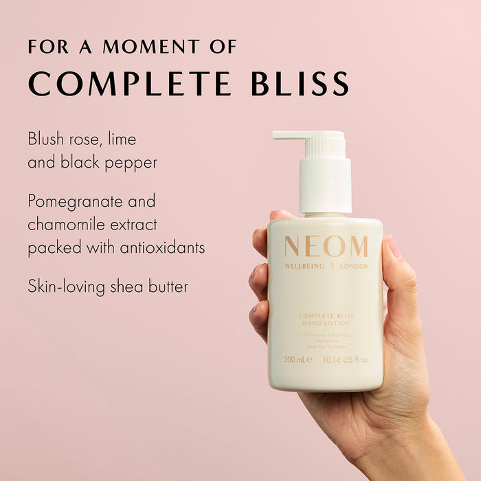 Hand holding NEOM Complete Bliss hand lotion bottle with ingredients like pomegranate, chamomile, and shea butter