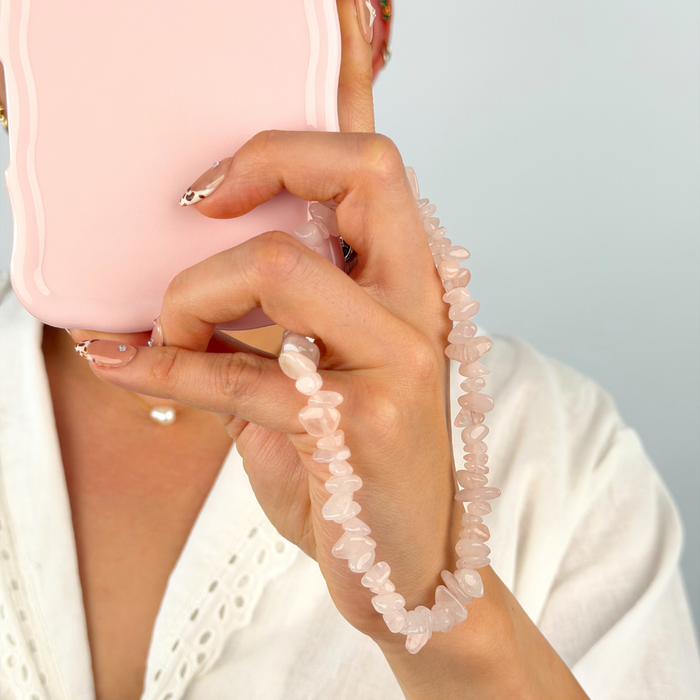 Girl with her rose quartz phone strap around her wrist attached to a pink phone case