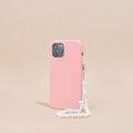 Pink smartphone case with clear Crystal Phone Strap stands upright against a beige background.