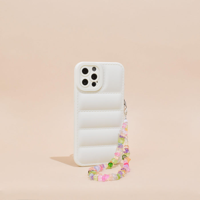 White quilted phone case with colorful crystal strap, displayed upright on a beige surface.