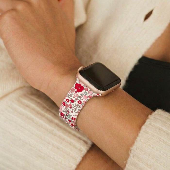 Floral-patterned Apple Watch strap on wrist, arm resting on a cream knit sweater.