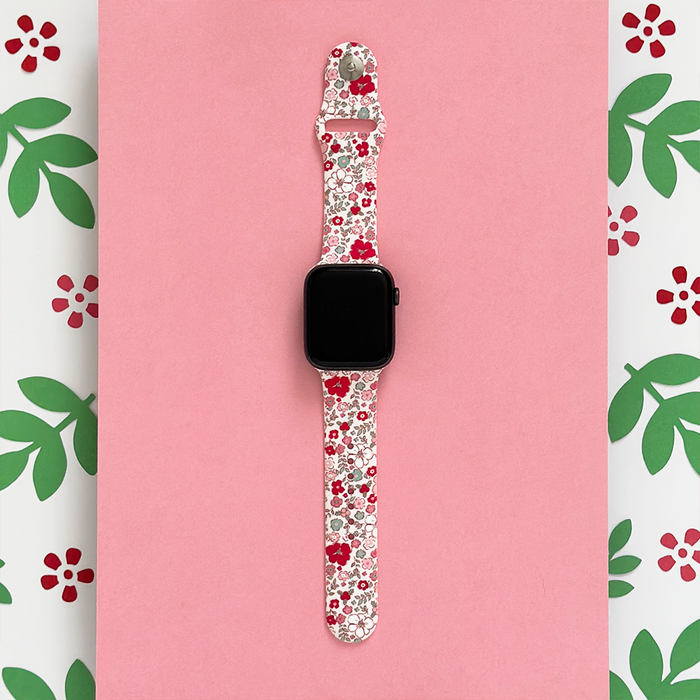 Apple Watch strap with pink and red floral pattern on a pink background.