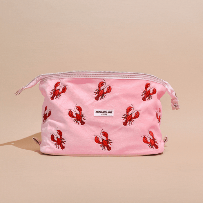 Pink velvet expandable makeup bag with red lobster print and a white Coconut Lane logo label.