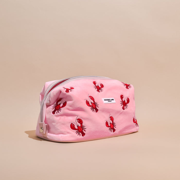 Expandable makeup bag with red lobster print on beige, pink velvet trim, and Coconut Lane branding.