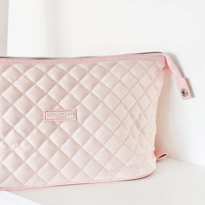 Quilted marshmallow pink expandable makeup bag by Coconut Lane with a zipper, displayed on a white surface.