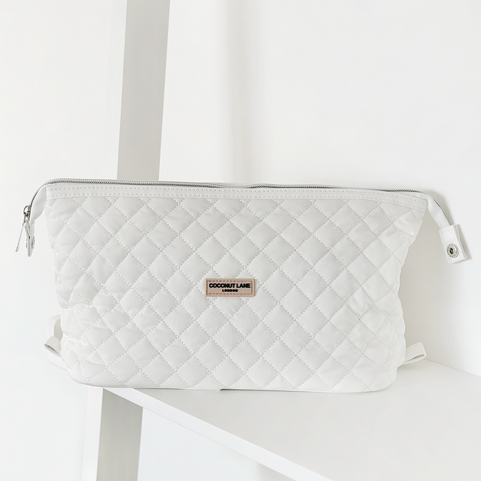 Quilted white coconut-pattern expandable makeup bag on a white shelf against a plain white background.