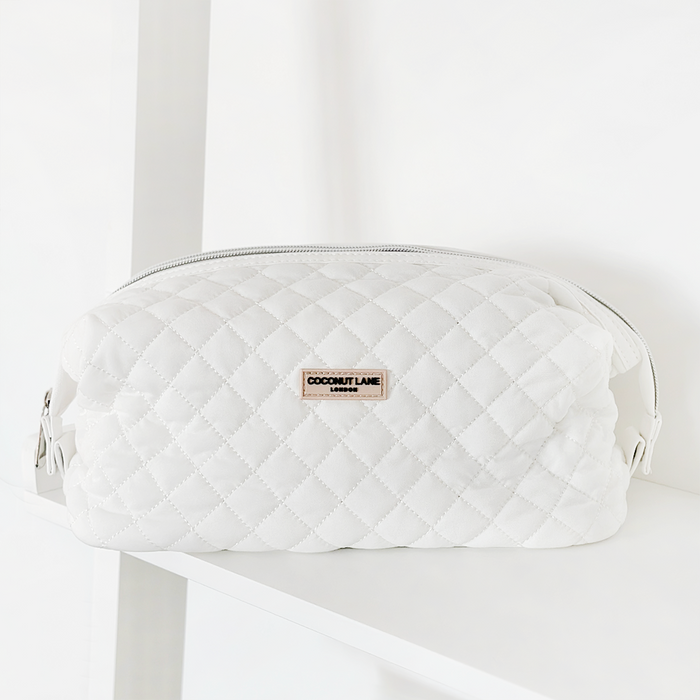 Quilted milky coconut-colored expandable makeup bag on a white surface with a white background.