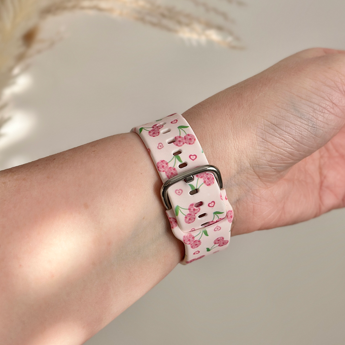 Coconut Lane Fitbit strap with pink cherry pattern on a light background, shown on a wrist.