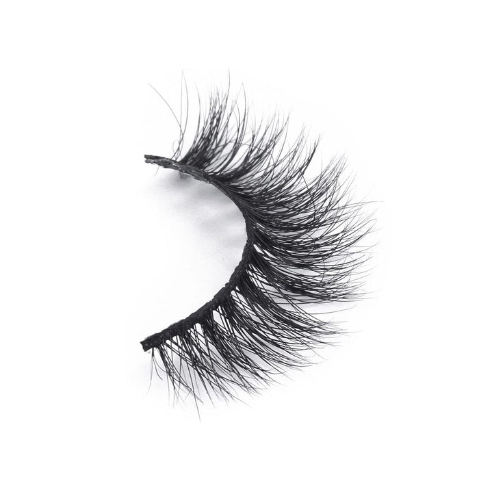 A single false eyelash strip with dense, black, and wispy fibers curves subtly for a dramatic look on a white background.