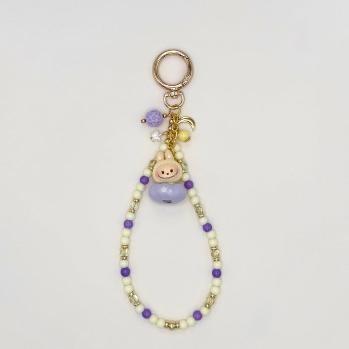 Beaded keychain with charms on a light gray background