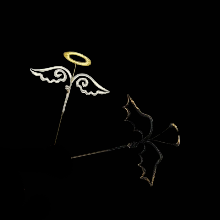 View of a pair of handmade Chanhua thread-wrapped brooches featuring a white angel wing with a gold halo and a black demon wing with gold tips.