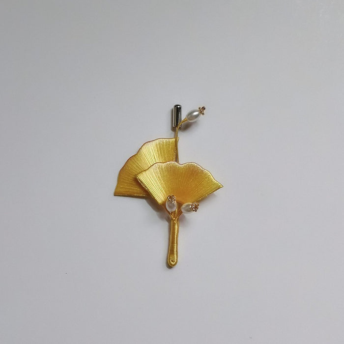 A traditional Chinese thread-wrapped (Chanhua) golden ginkgo leaf pin on a plain background, showing artisanal 3D textures.