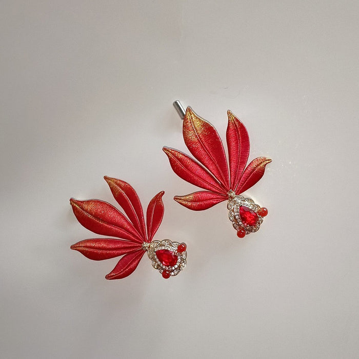 A pair of traditional Chinese thread-wrapped (Chanhua) goldfish pins on a plain background, showing artisanal 3D textures.