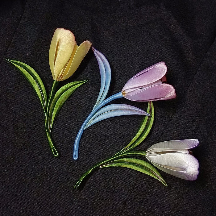 Close-up of handmade thread-wrapped tulip jewelry on a dark fabric background, showing the fine artisanal texture.