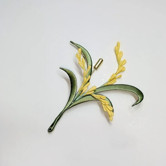 Handcrafted Chanhua wheat ear brooch featuring yellow thread-wrapped grains and green leaves on a white background.