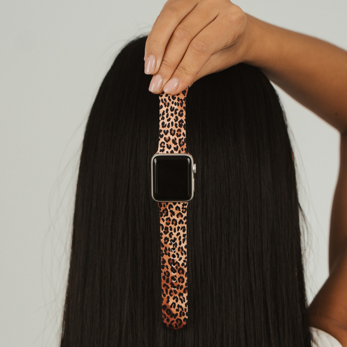 Hand holding Coconut Lane leopard print Apple Watch strap against long, straight black hair.