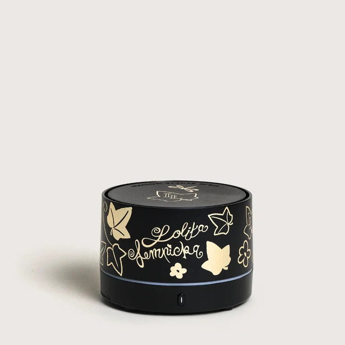 Black cylindrical portable diffuser with gold designs and text on a light gray background