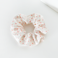 Coconut Lane scrunchie with a pink heart pattern on white fabric.