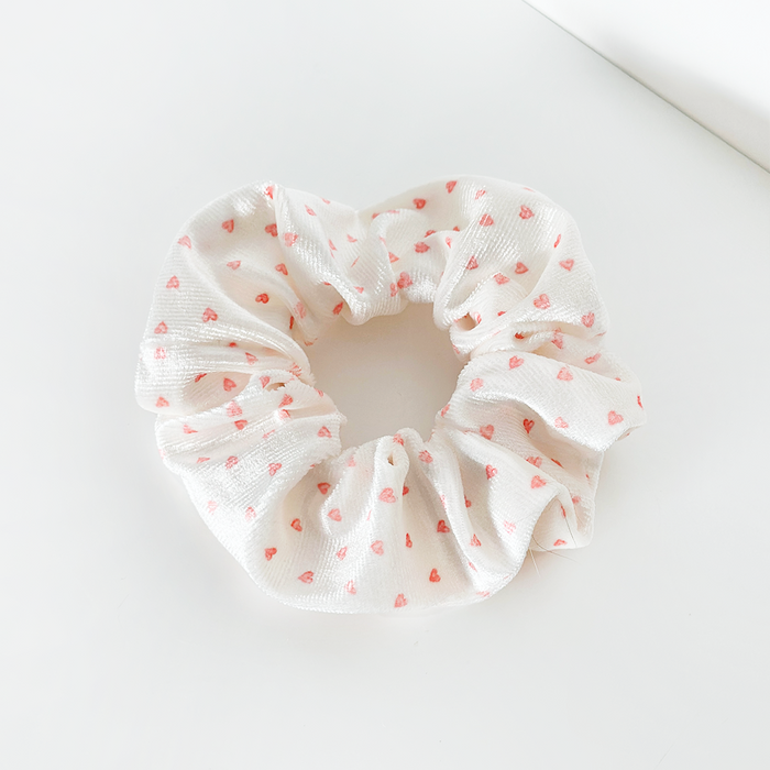Coconut Lane scrunchie with a pink heart pattern on white fabric.
