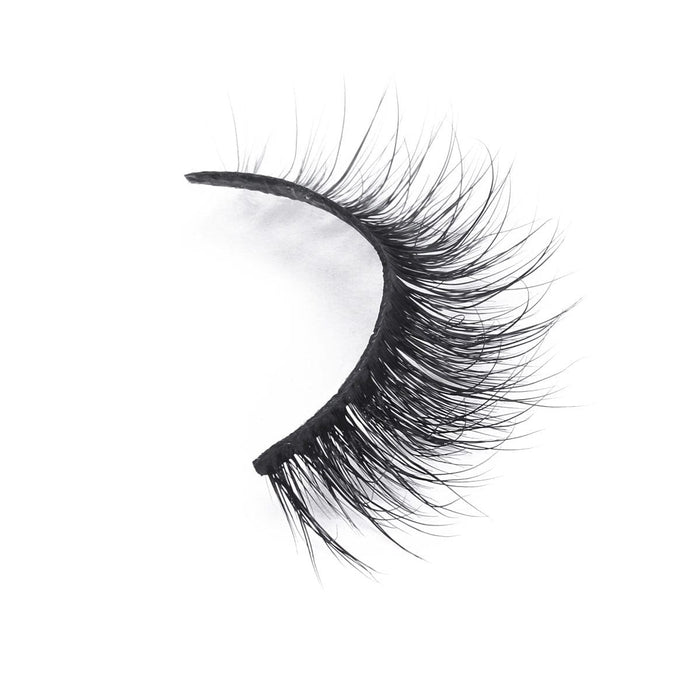 A single dramatic false eyelash with thick, long black fibers curves elegantly against a white background.