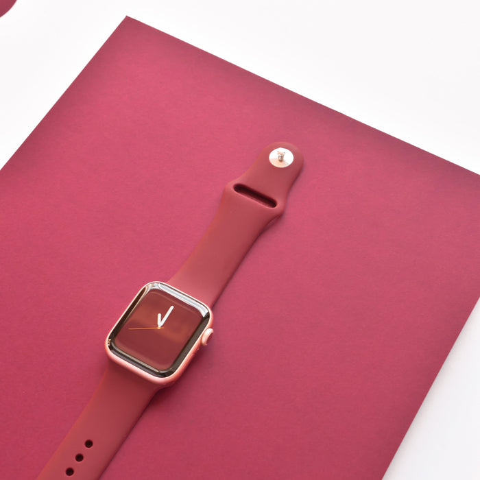 Burgundy Coconut Lane NAKD Apple Watch strap displayed on a red background, watch face showing near 12 oclock.