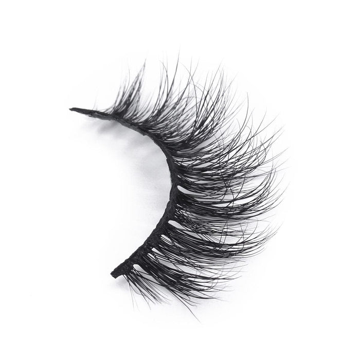 A single false eyelash strip features dense, long, and wispy black lashes for a dramatic look, displayed against a white background.
