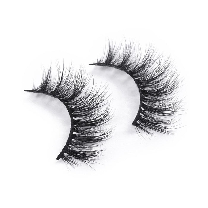 Thick, wispy black false eyelashes elegantly curve against a white background, creating a bold and glamorous look.