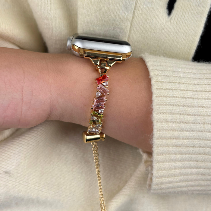 Gold Apple Watch strap with crystal details, worn with a cream sweater.