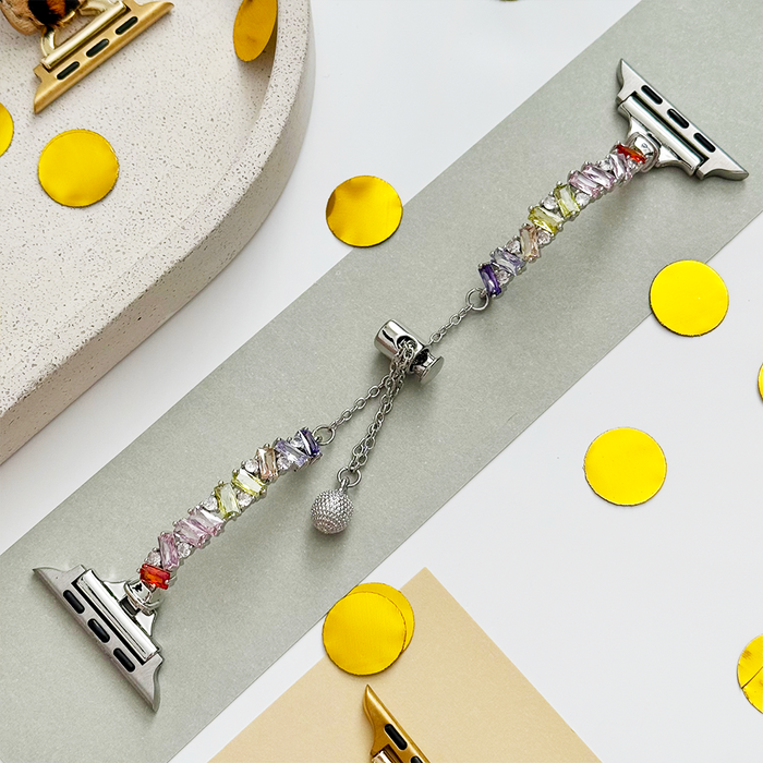 Silver Apple Watch strap with colorful beads, a small charm, and scattered gold confetti accents.