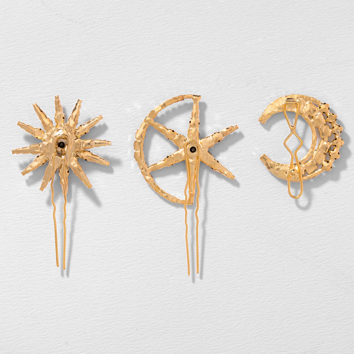 Three gold brooches with star, moon, and sun designs on a light gray background