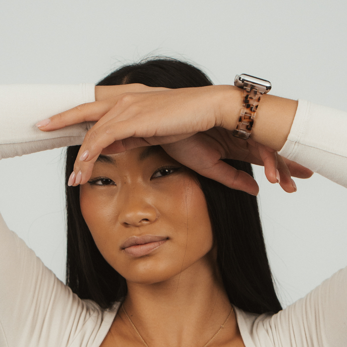 Woman with long black hair wearing a Slim Luxe Ivory Tort watch strap and a neutral top.
