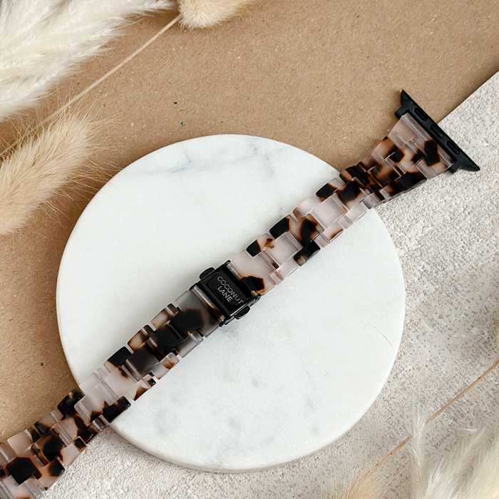 Slim Luxe Ivory Tort Apple Watch strap with marbled pattern, displayed on a white marble tray against a beige background.