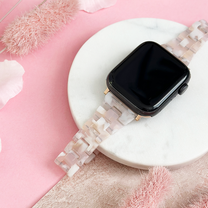 Slim Luxe Rose Apple Watch strap by Coconut Lane on a white marble plate against a pink background.