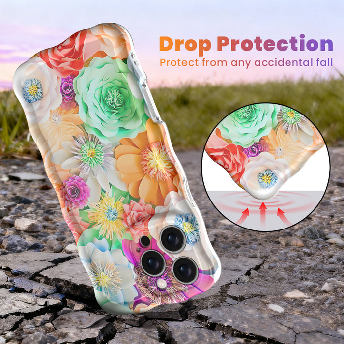 Hand holding a vibrant floral iPhone case featuring roses, daisies, and colorful blooms in pink, teal, and yellow with wavy edges.