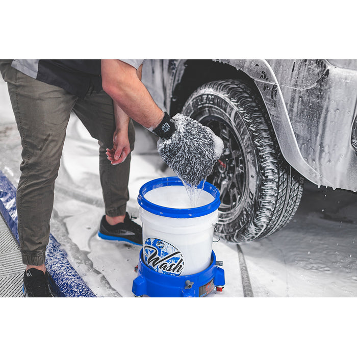 Black and White microfiber wash mitt soaked in cleaning solution in front of a foam covered car