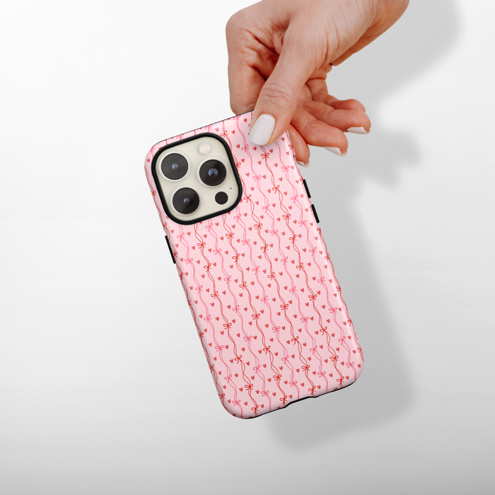 Phone case with pink pattern held by a hand on a light gray background