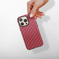 Hand holding a Coconut Lane Tough MagSafe phone case with mulberry and white stripes on a light background.