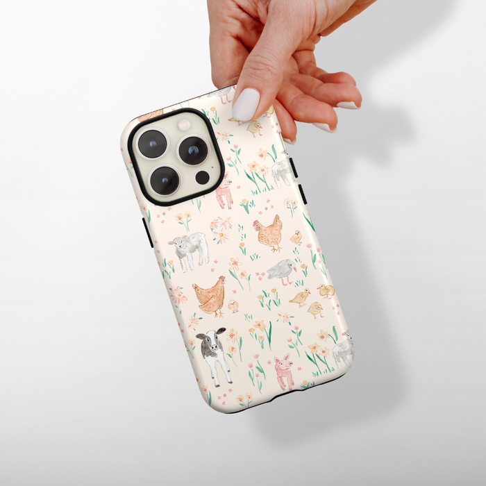 Hand holding a Coconut Lane Tough Phone Case with playful chicken, cow, and sheep illustrations on a white background.