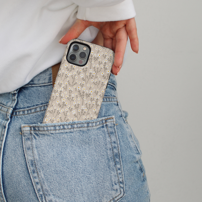Nude floral MagSafe phone case partly tucked into the back pocket of light blue jeans.