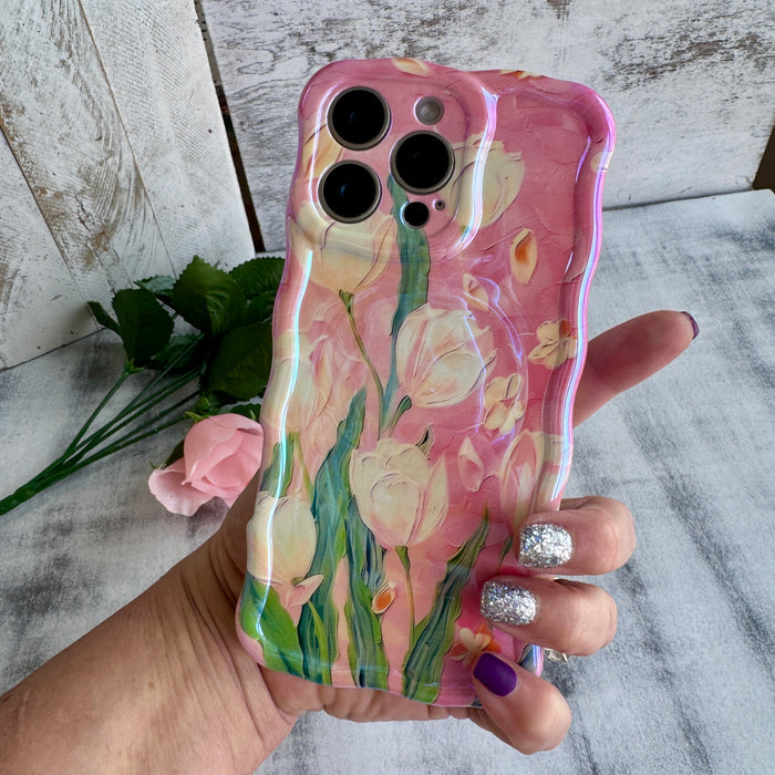 Pink wavy iPhone case featuring painterly white and pink tulips with green stems and iridescent finish.